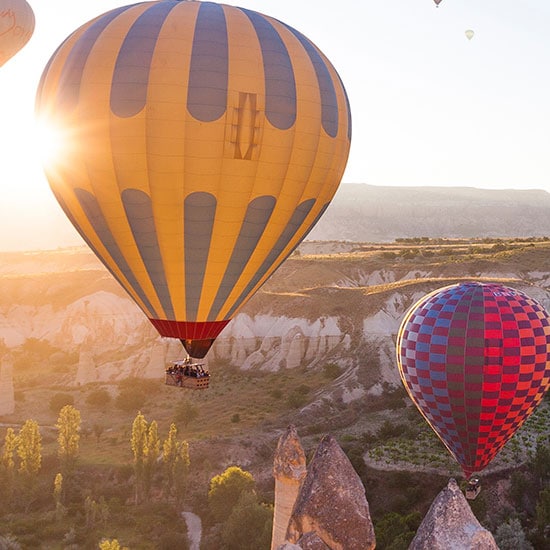 hot air balloons floating above the valley at sunrise