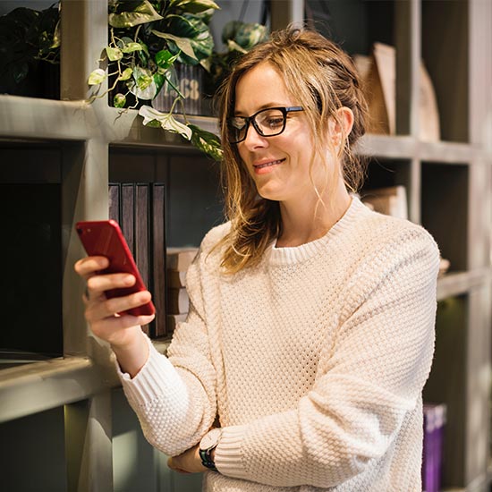 happy woman checking bills on mobile phone