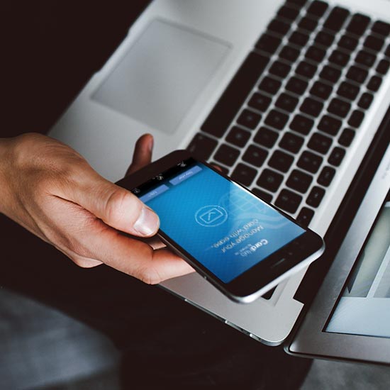 man with laptop, holding phone with CardHub app open