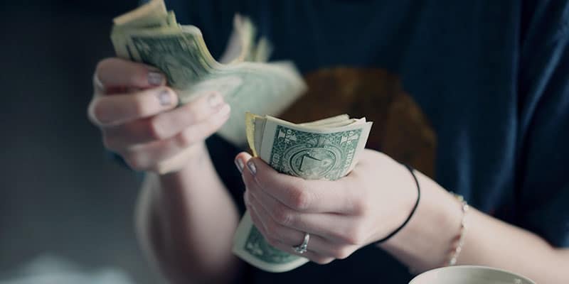 close up of hands counting dollar bills