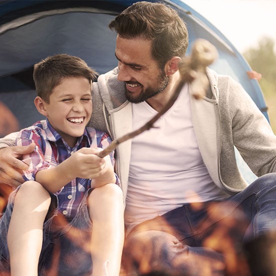 father and son camping together, roasting marshmellows