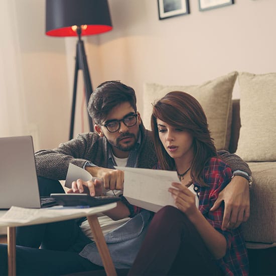 thoughtful couple checking their bills and using a calculator