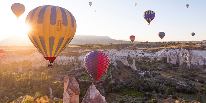 hot air balloons floating above the valley at sunrise