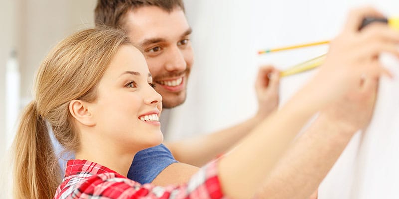 couple remodeling their home, measuring a wall