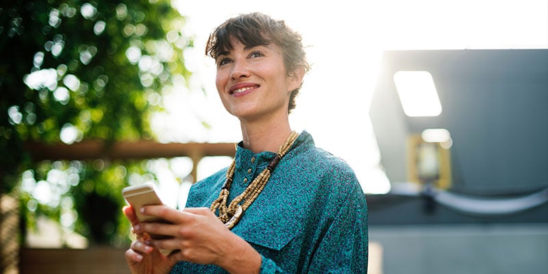 confident woman checks her phone outdoors