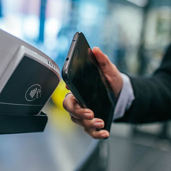 person scanning their phone next to a tap-to-pay terminal