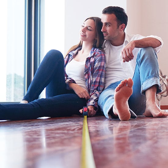 young couple in their new home with a measuring tape