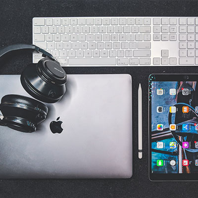 flatlay of headphones, laptop, keyboard, and tablet