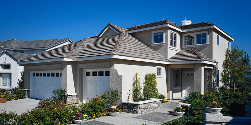 exterior of a stucco home, tight green landscaping surrounds