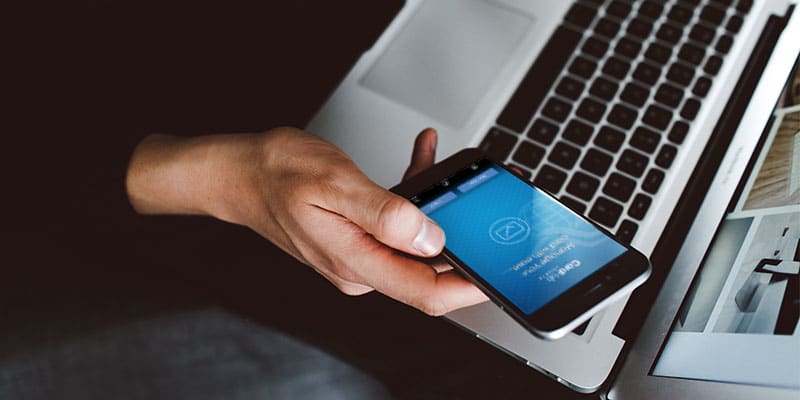man with laptop, holding phone with CardHub app open