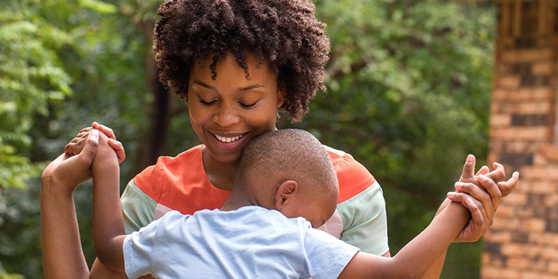 Black mother holding her son and smiling