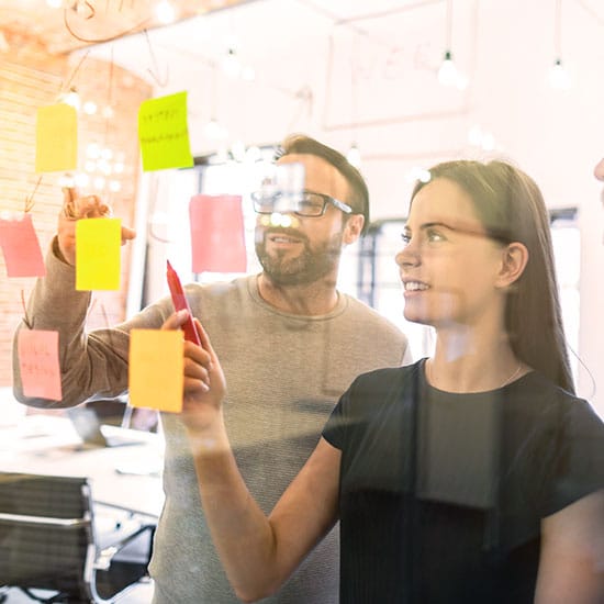 business partners looking over their sticky note chart together