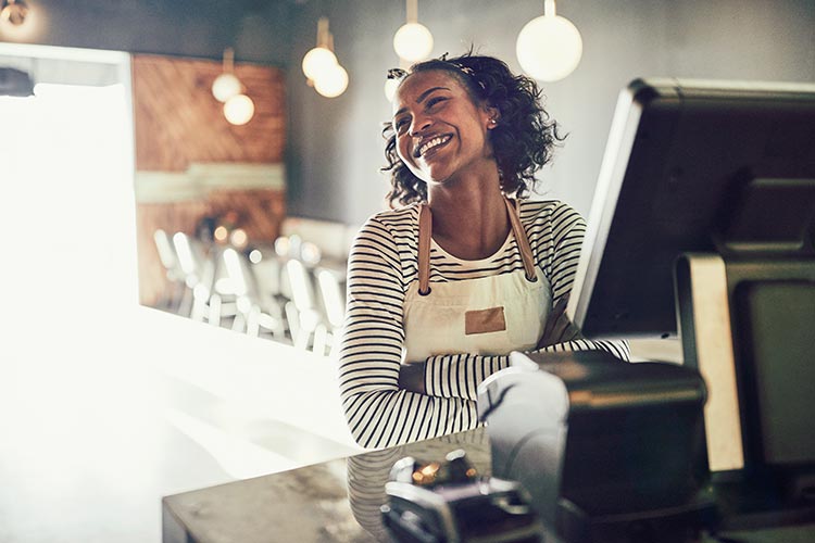 smiling female cashier standing at card terminal