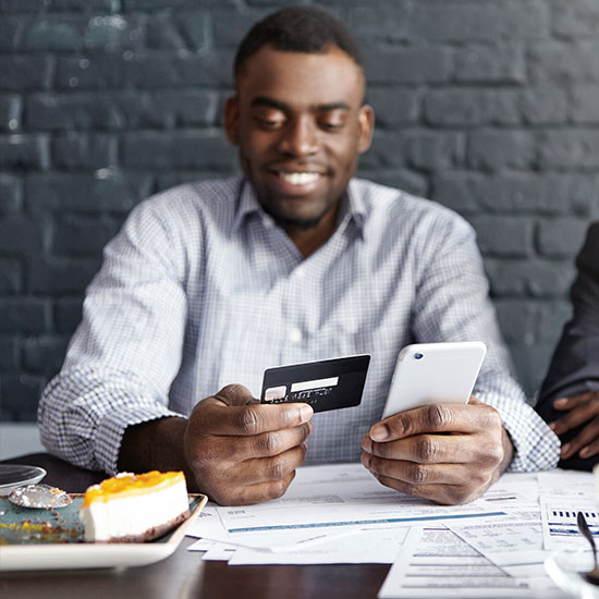 businessman at lunch with a credit card and smartphone in his hands