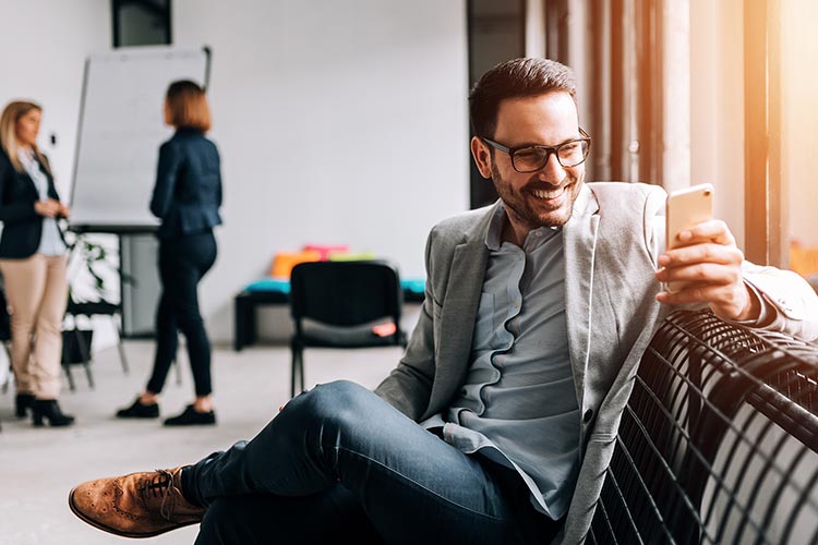 businessman checking his mobile banking, business partners out of focus in the background