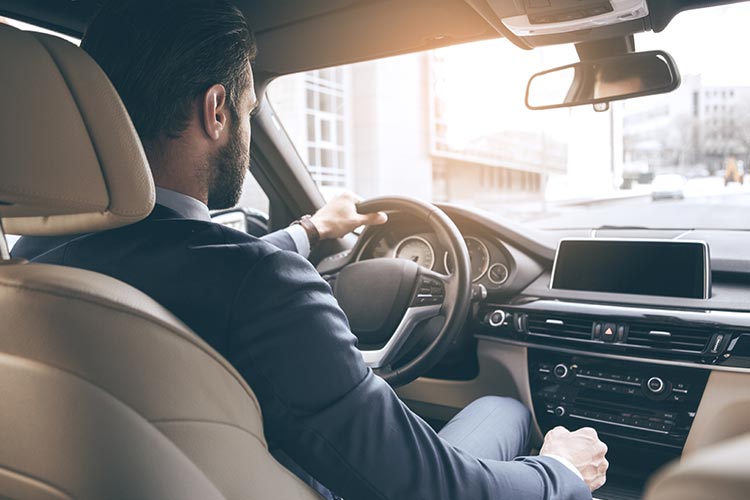 man wearing a suit driving a manual vehicle