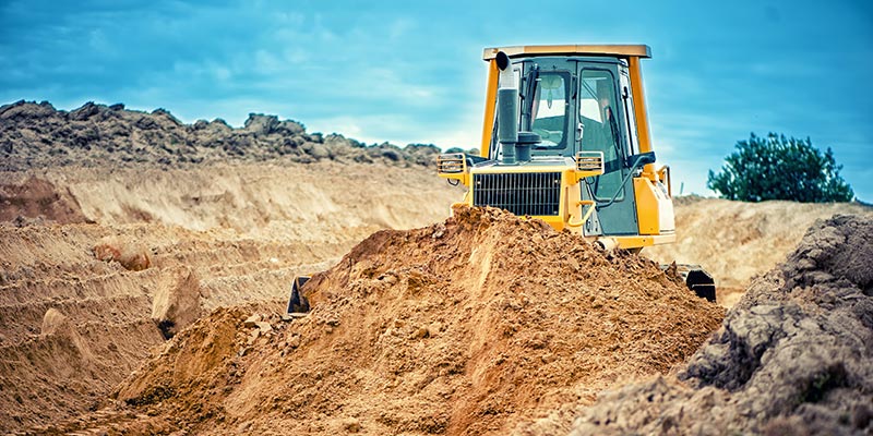 bulldozer pushing dirt in empty lot