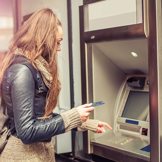 woman holding her debit card at the ATM