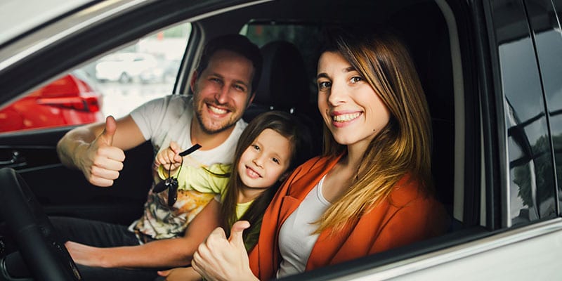 happy family sitting in their new car