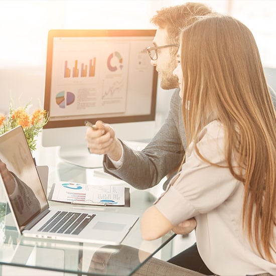 man and woman looking at finance graphs on computer