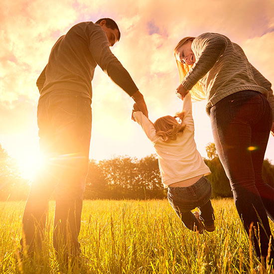 parents holding child's hands in an open field