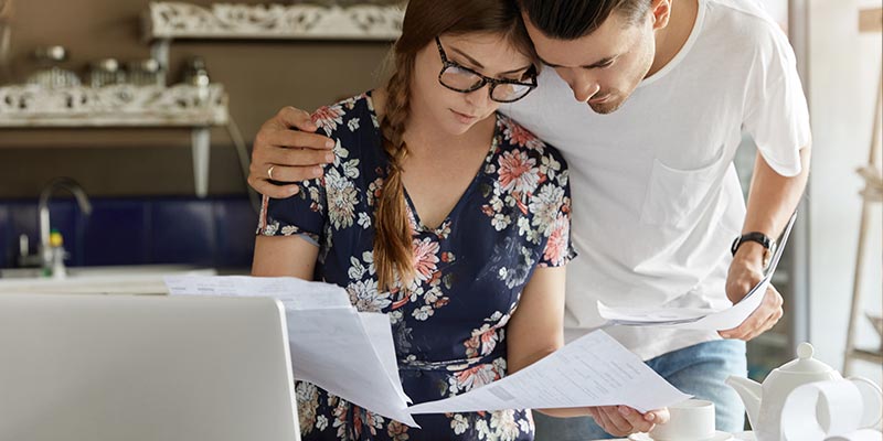 couple looking over some documents at their computer