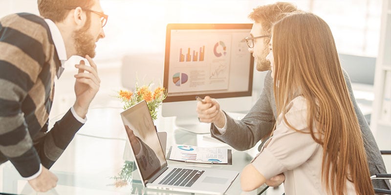 man and woman looking at finance graphs on computer