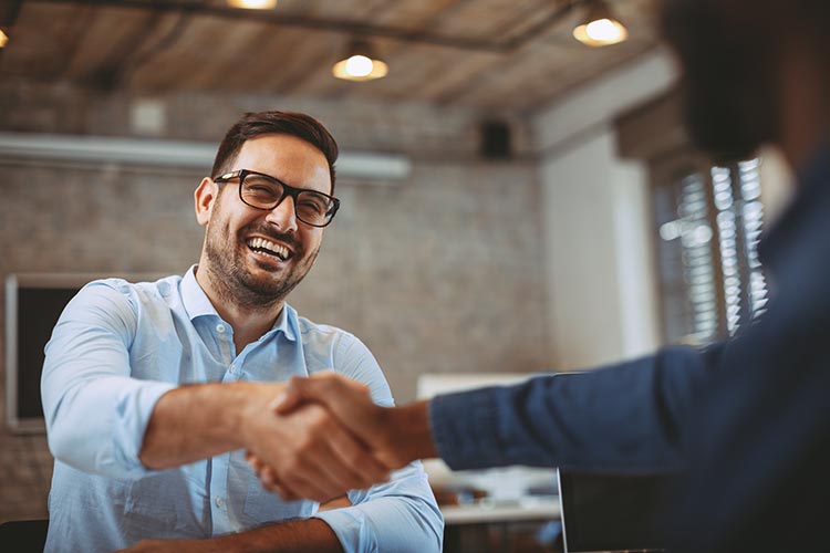 out-of-focus financial advisor shaking hands with a happy, smiling client