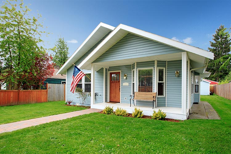 modest home with trimmed lawn and USA flag flying outside