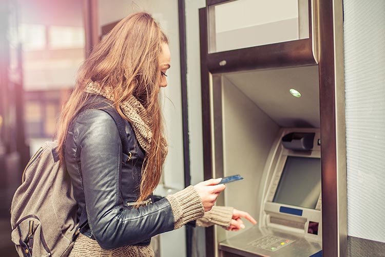 woman holding her debit card at the ATM