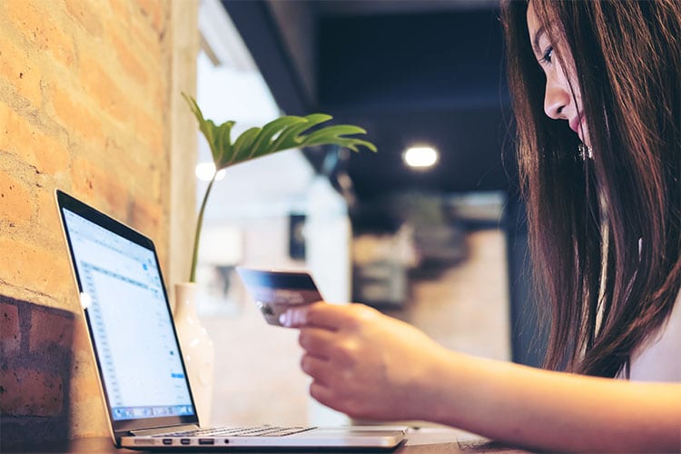 woman holding a credit card and looking at her computer