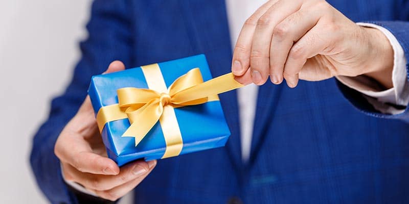 man holding a blue gift box with a gold ribbon