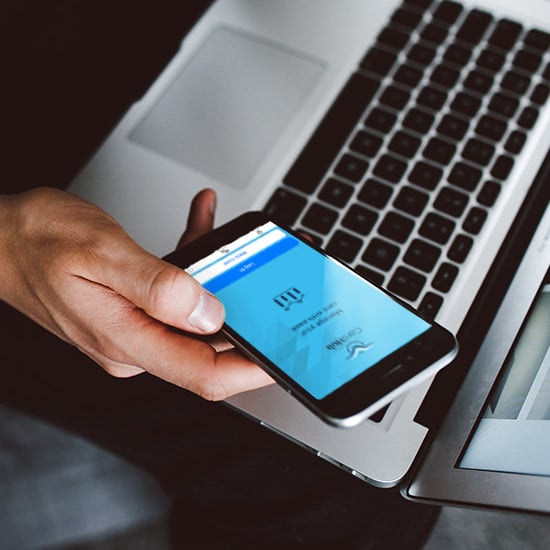 man with laptop, holding phone with CardHub app open