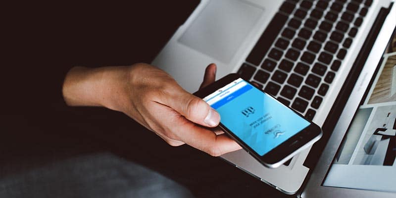 man with laptop, holding phone with CardHub app open