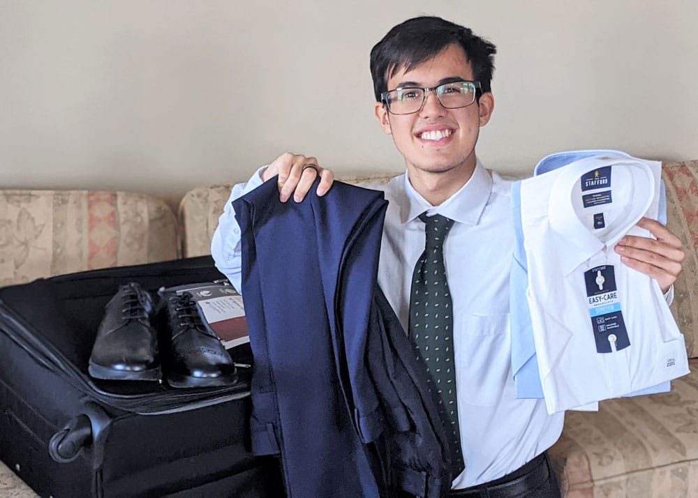A missionary in glasses showing his new shirts and pants.