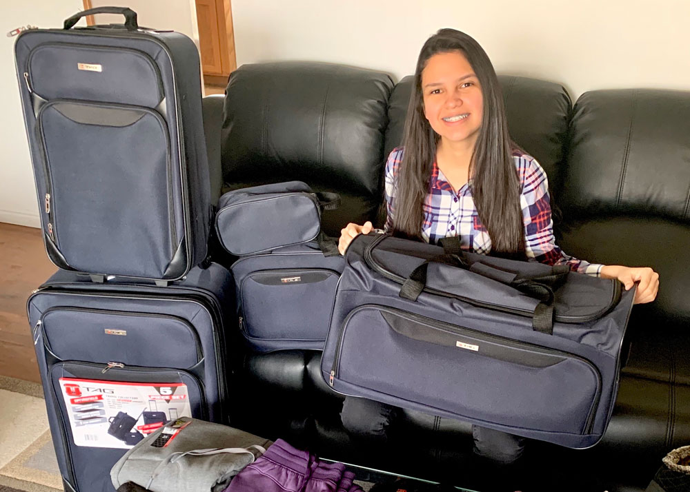 A sister missionary sitting on a couch with her set of luggage
