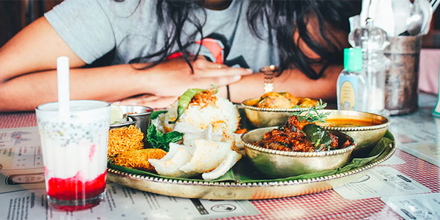 A woman admiring a plate of food in front of her.