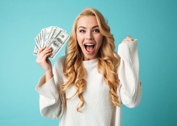 A woman holding dollar bills with a face of excitement.