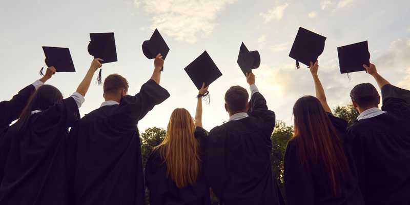 Students in graduation robes throwing caps into the air