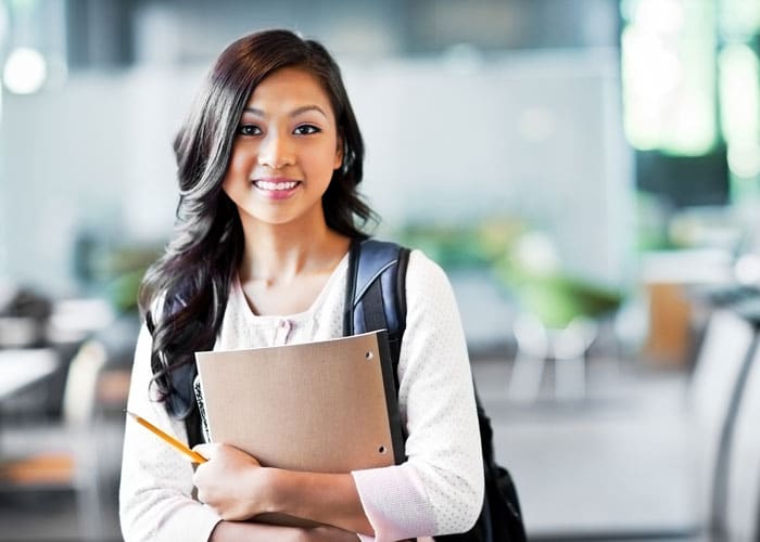 A young female student carrying her bag and notebook