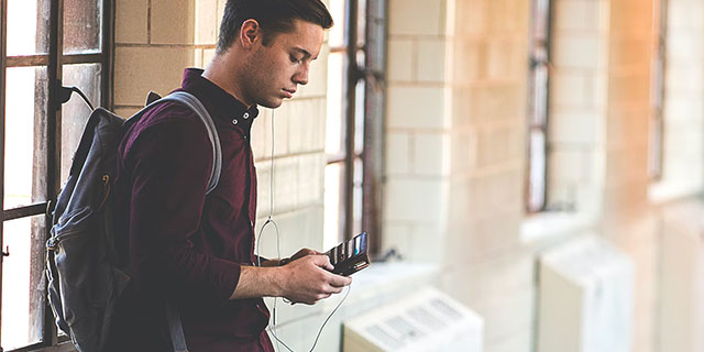 Male student in a hallway looking in his wallet.