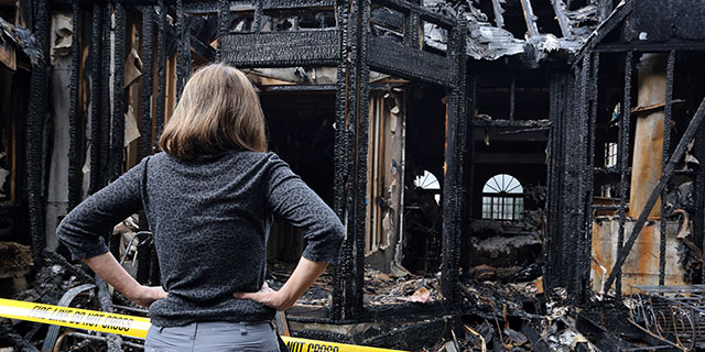 A woman looking into a burnt down home
