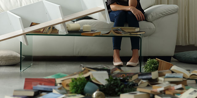 A woman sitting among the toppled things in her apartment